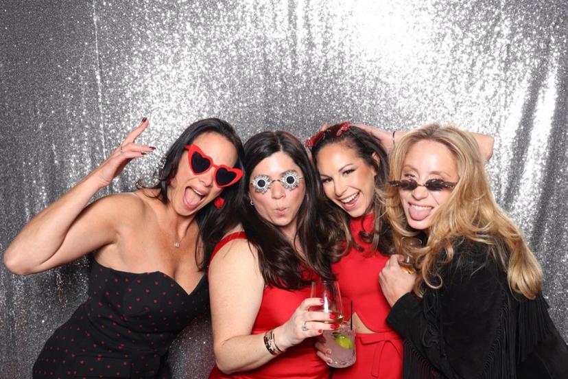 Party guests in front of a silver sequin photo booth backdrop