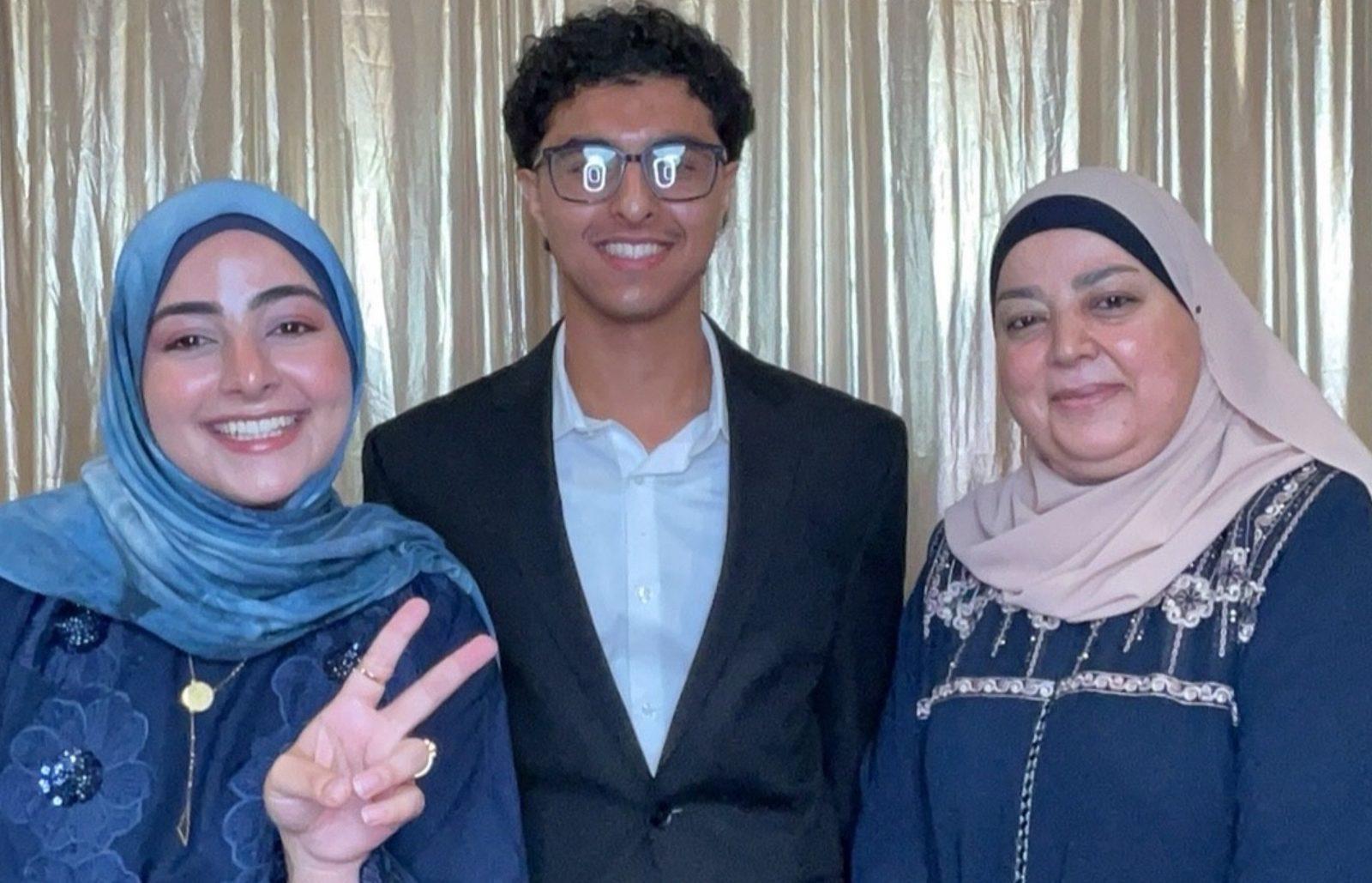 Graduate posing with family members flashing a peace sign in a photo booth