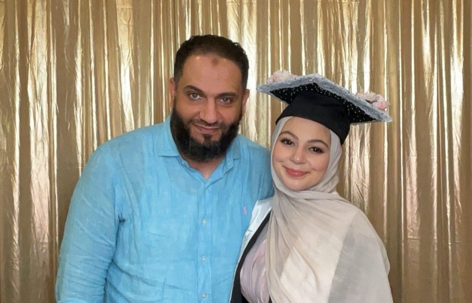 Father and graduate daughter smiling together in an event photo booth