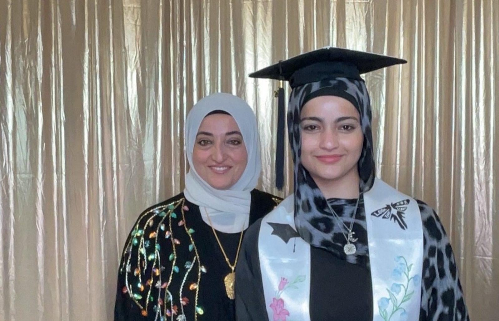 Graduate in cap posing with her mother in a Philadelphia photo booth
