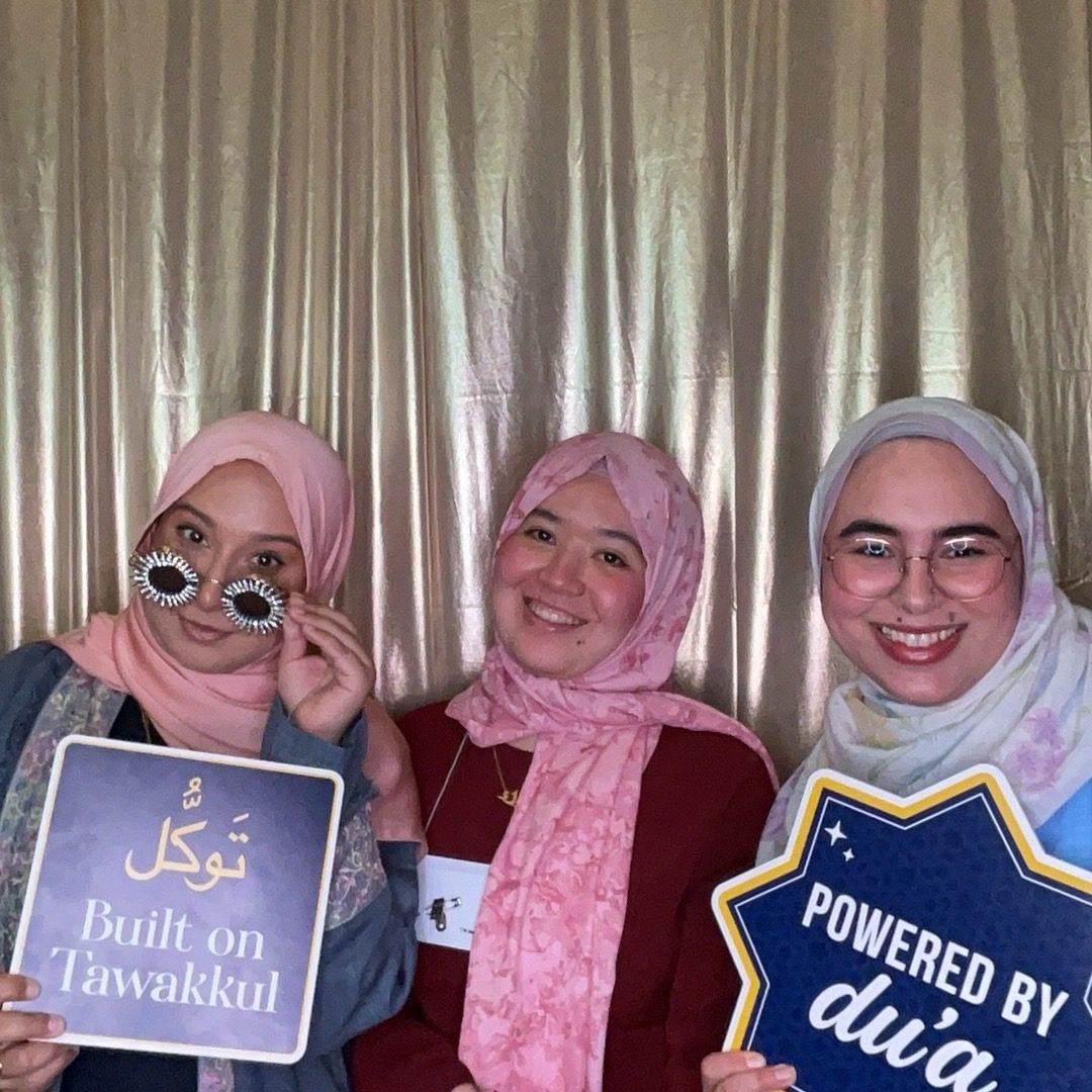 Three guests holding custom prop signs in an event photo booth