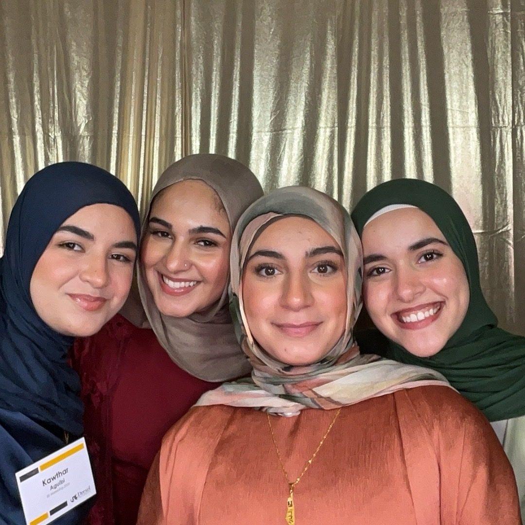 Friends striking playful poses in a photo booth at a college banquet